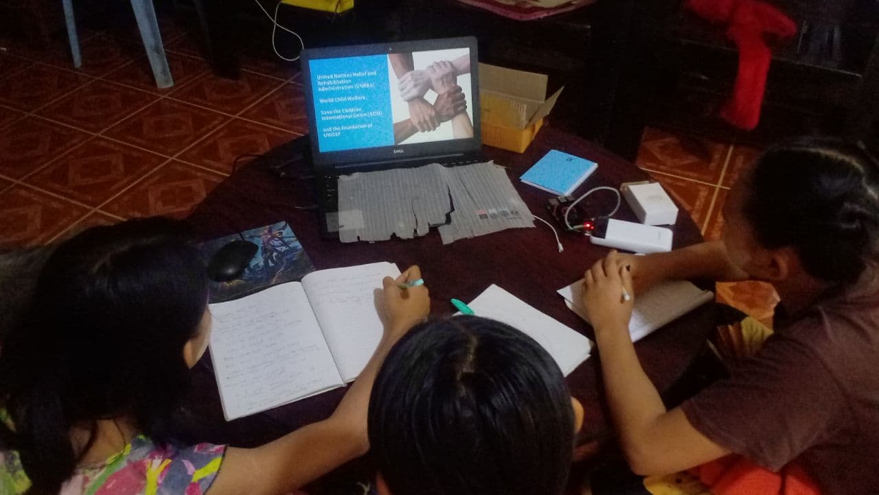 Students studying together around an eduLamp-powered laptop