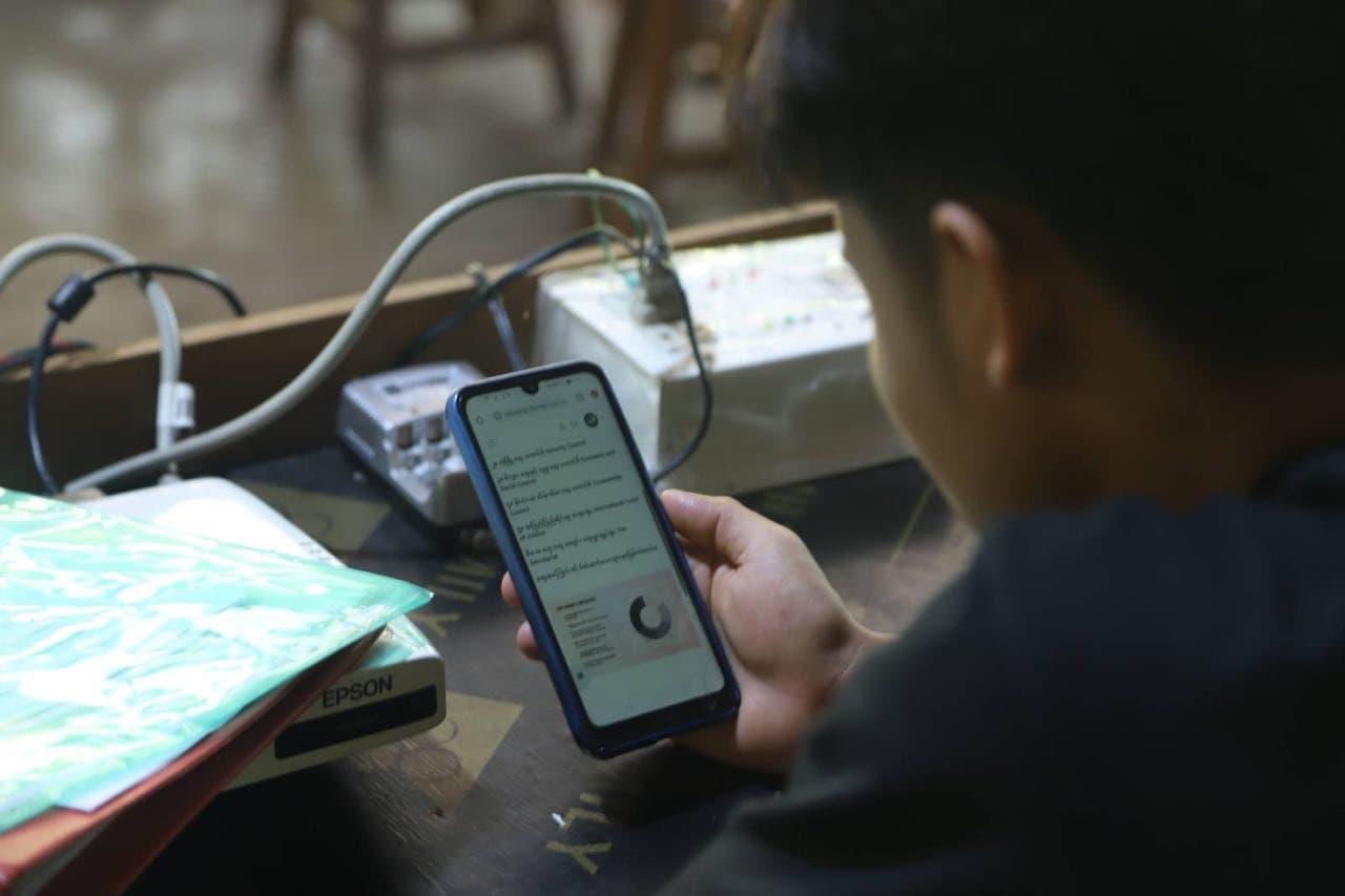 A student reading lessons on a phone connected to an eduLamp Box